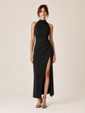 A woman wearing the Elévaison Maren black ruched halter-neck maxi dress with a side slit, viewed from the front, against a light beige studio background.