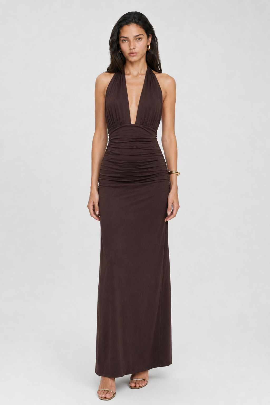 A woman wearing the Elévaison Vivienne coffee deep V-neck halter maxi dress with a ruched waist, viewed from the front, against a light gray studio background.