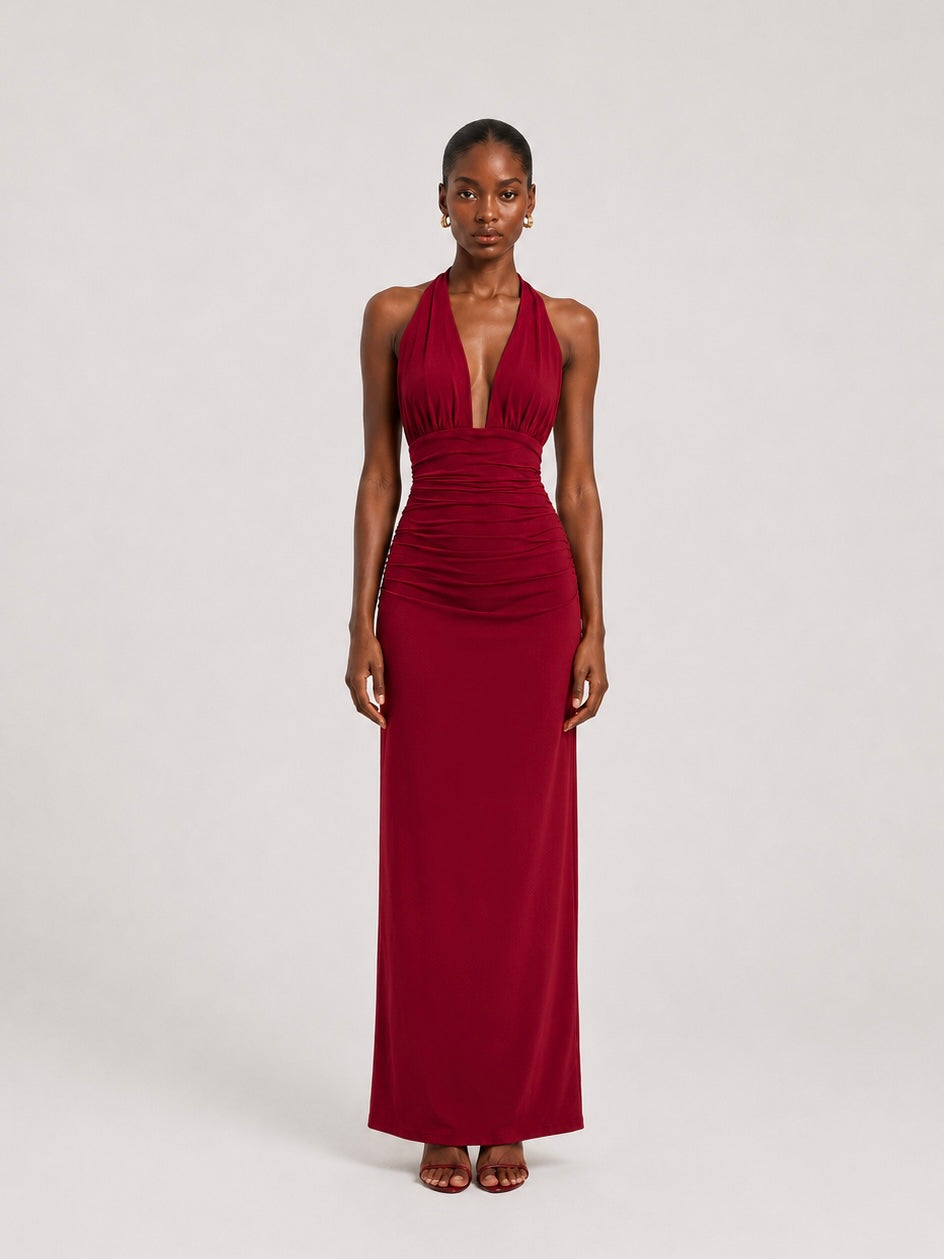 A woman wearing the Elévaison Vivienne burgundy deep V-neck halter maxi dress with a ruched waist, viewed from the front, against a light gray studio background.