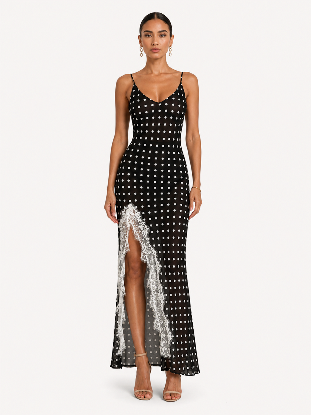 A woman wearing the Elévaison Lucienne Midnight Polka lace-trim maxi dress with a side slit, viewed from the front, against an ivory studio background.