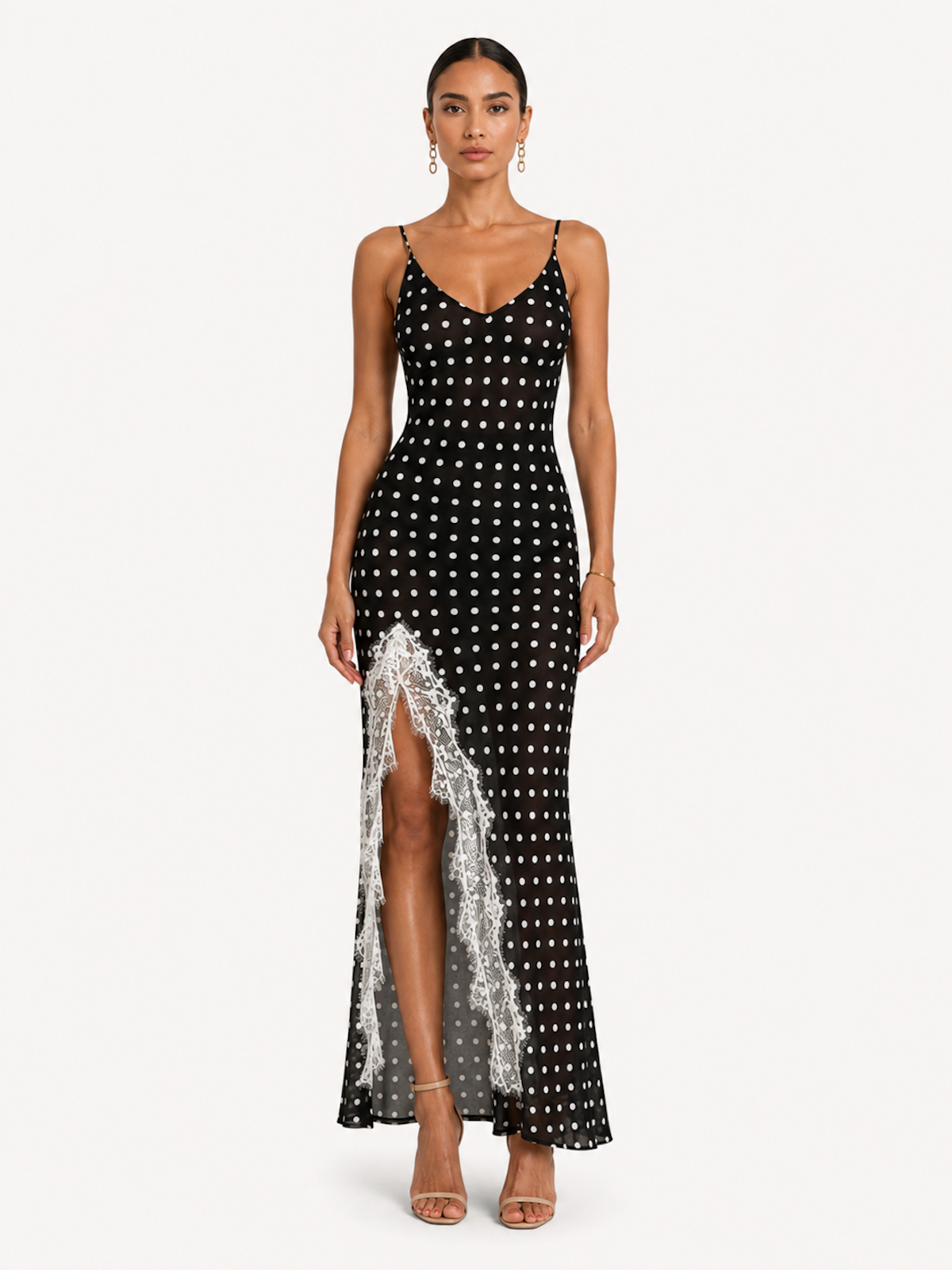 A woman wearing the Elévaison Lucienne Midnight Polka lace-trim maxi dress with a side slit, viewed from the front, against an ivory studio background.