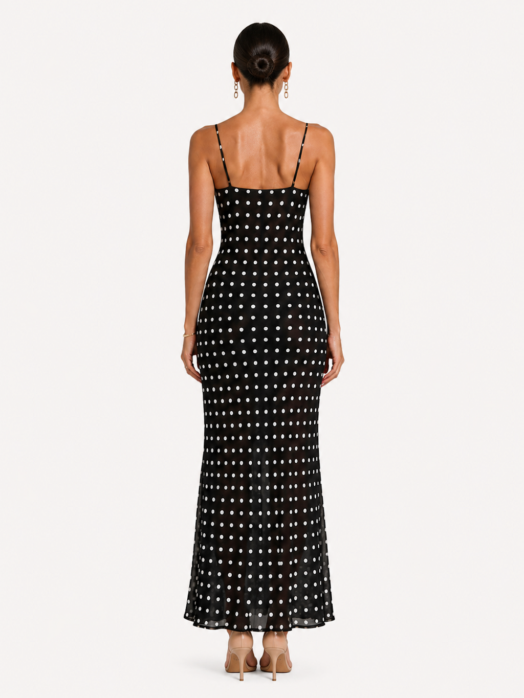 A woman viewed from the back wearing the Elévaison Lucienne Midnight Polka lace-trim maxi dress with a side slit, against an ivory studio background.