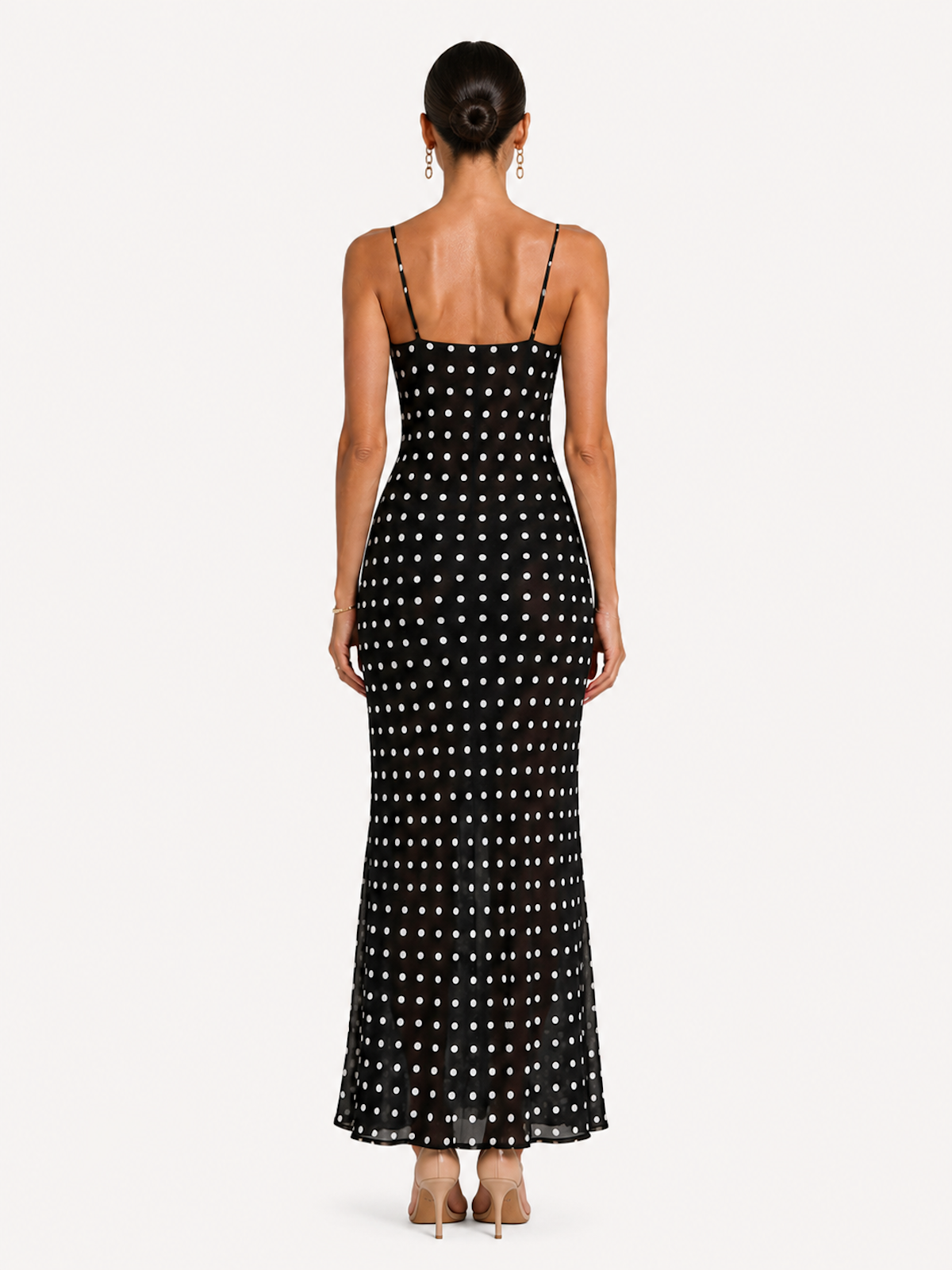 A woman viewed from the back wearing the Elévaison Lucienne Midnight Polka lace-trim maxi dress with a side slit, against an ivory studio background.