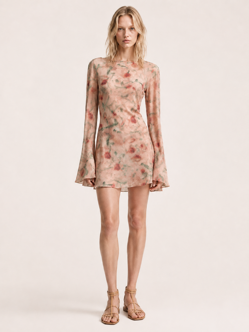 A woman wearing the Elévaison Rosy Blushed Garden watercolor-floral bell-sleeve mini dress, viewed from the front, against a light beige studio background.