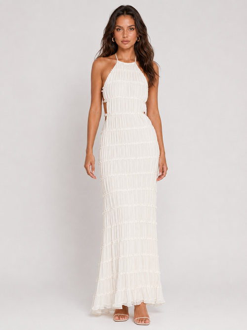 A woman wearing the Elévaison Corinne white tiered-ruffle halter maxi dress, viewed from the front against a light gray studio background.