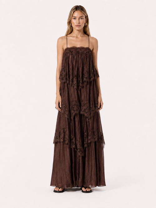 A woman wearing the Elévaison Delphine Coffee layered-lace babydoll maxi dress, viewed from the front against a light gray studio background.