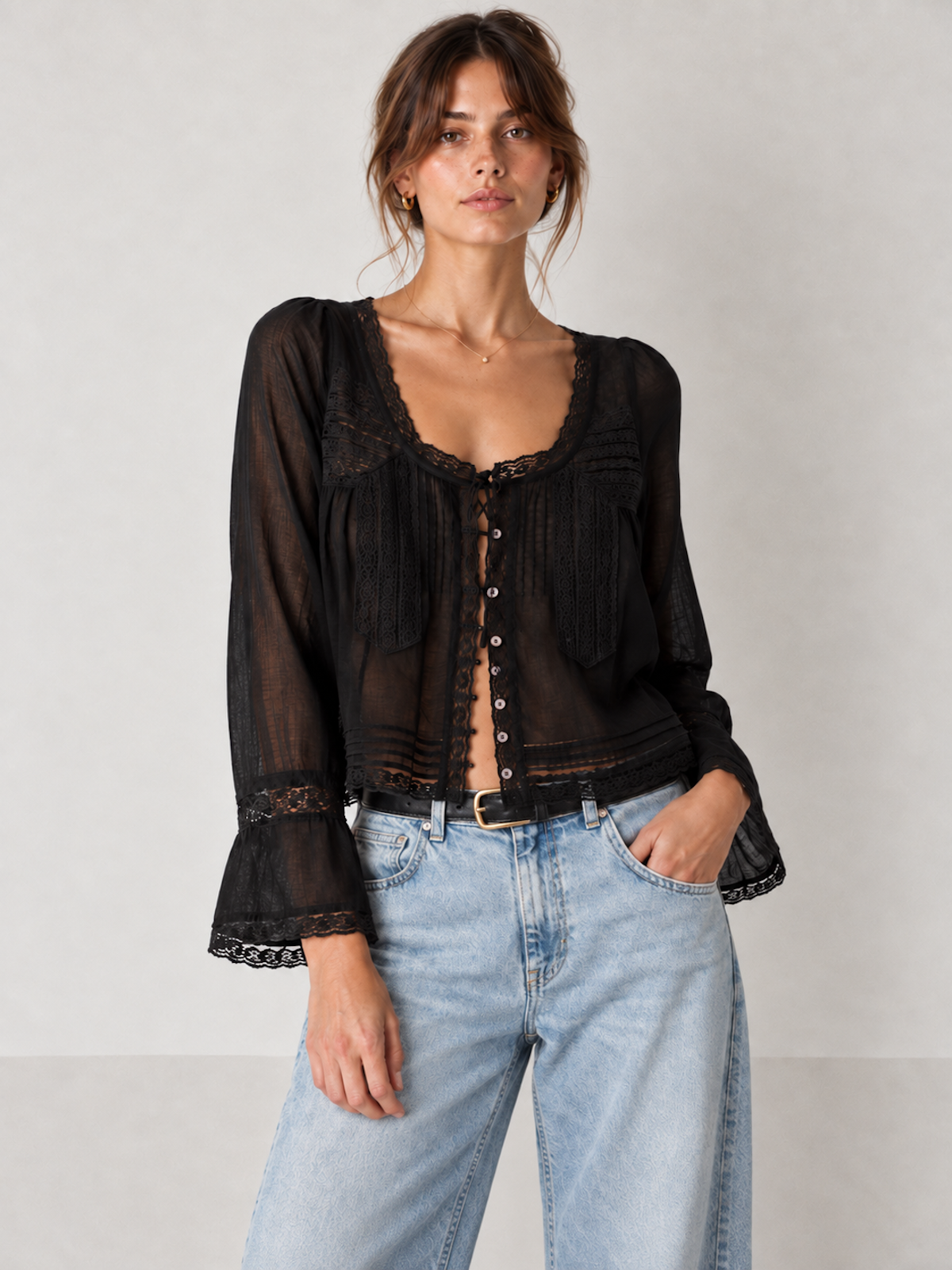 Front view of the black Elévaison Celine Blouse with a lace-trim tie neckline and bell sleeves against a light gray seamless backdrop.