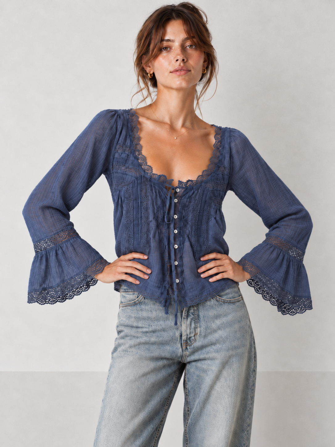 Front view of the navy Elévaison Celine Blouse with a lace-trim tie neckline and bell sleeves against a light gray seamless backdrop.