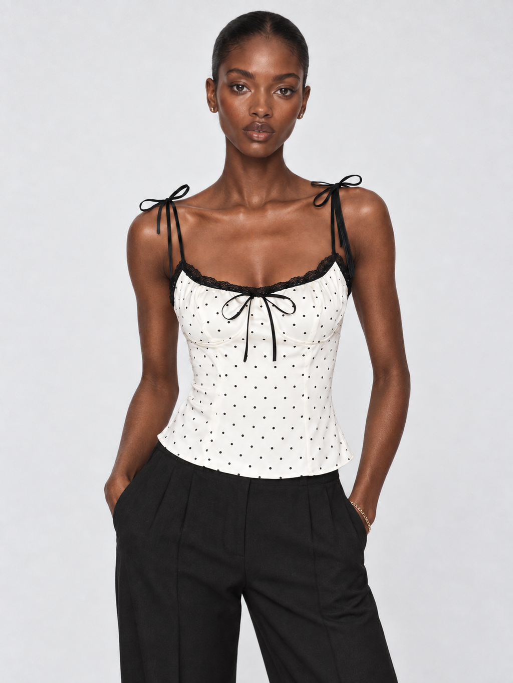 Model wearing the Porcelain Microdot Elévaison Elowen Sleeveless Top with a lace-trim neckline in a pale gray studio.