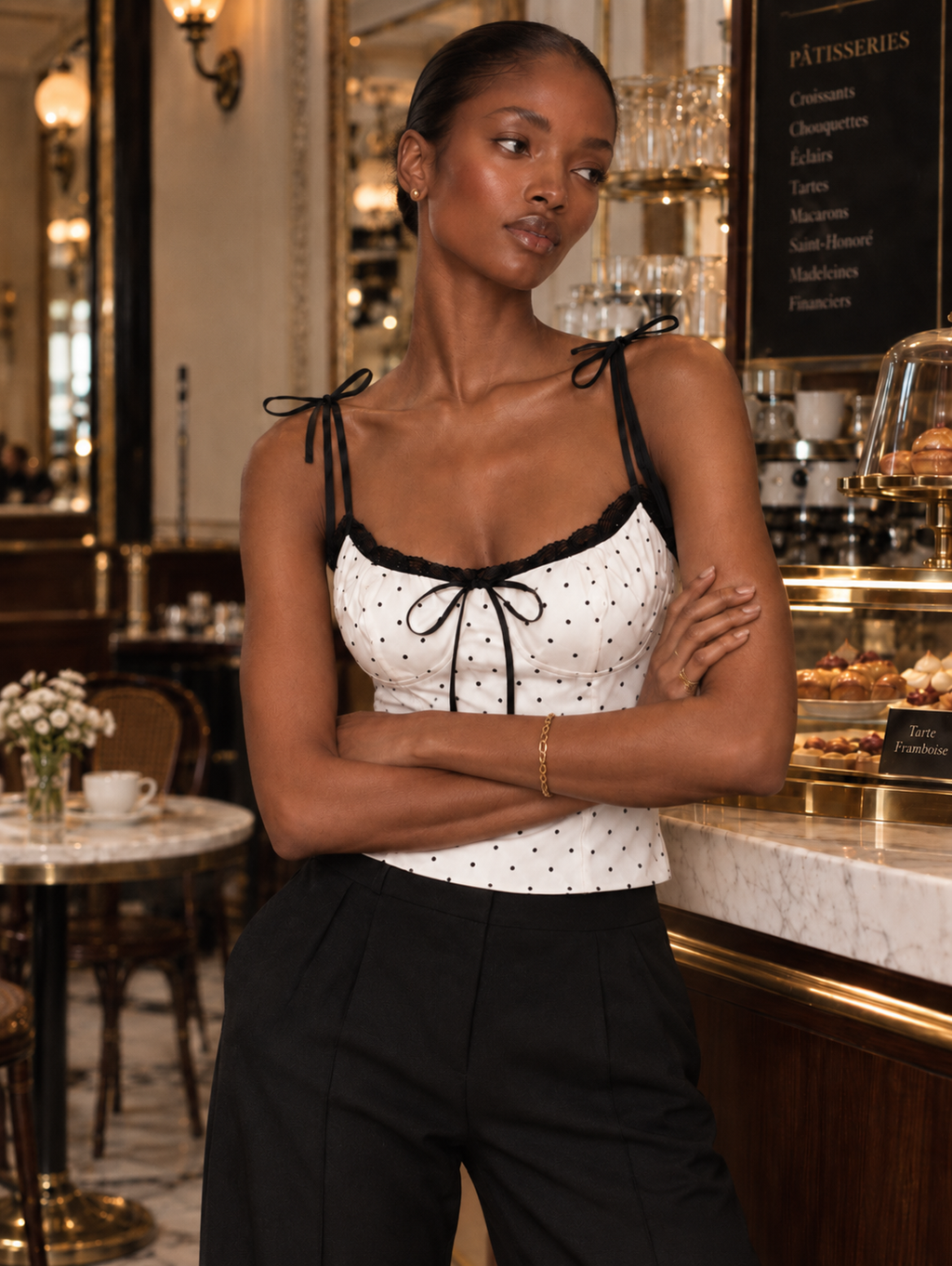 Model wearing the Porcelain Microdot Elévaison Elowen Sleeveless Top with shoulder ties and contrast lace in a café.