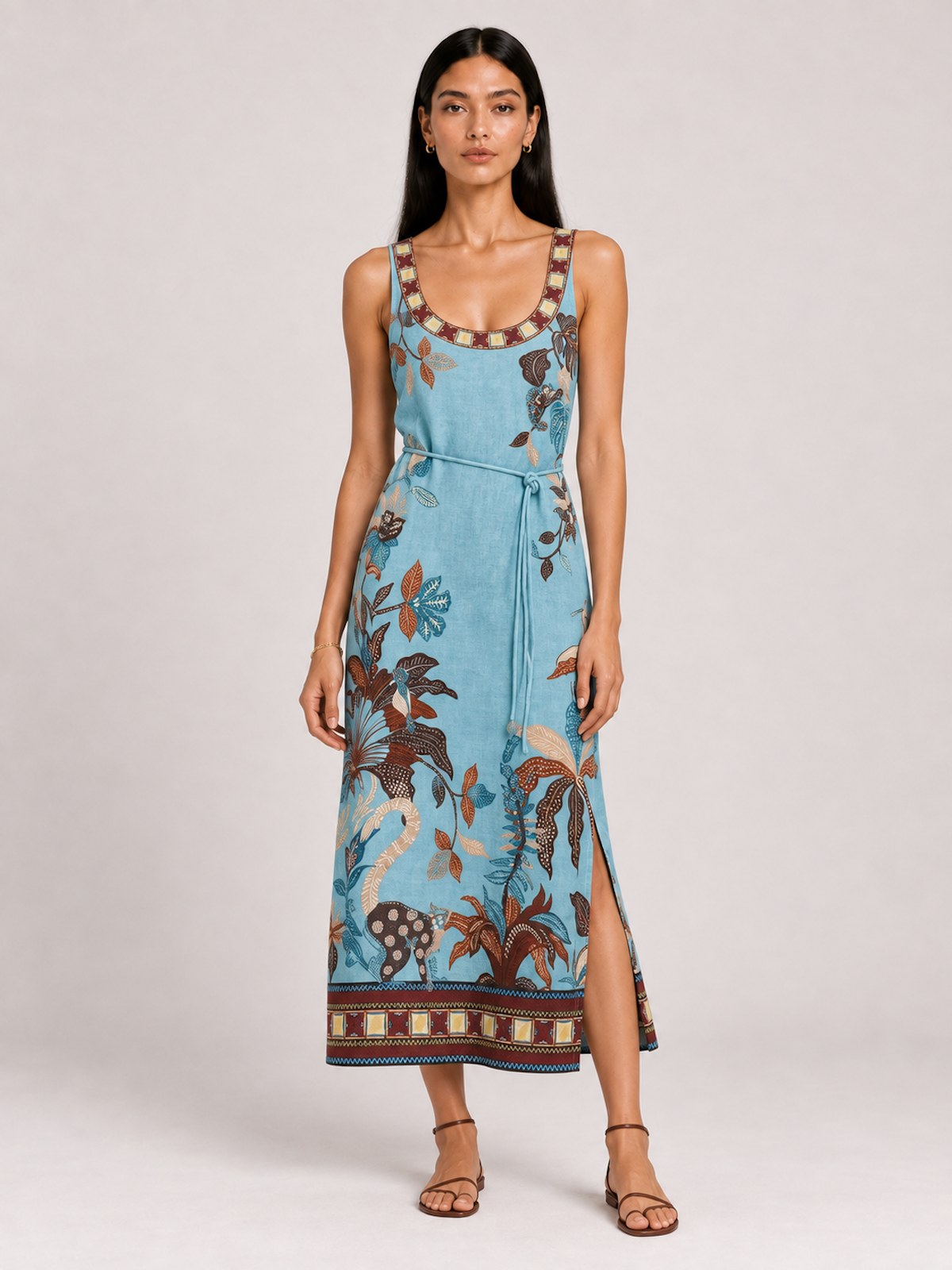 Model wearing the Botanical Lagoon Elévaison Daria Dress with a scoop neck, tie waist and floral border print in studio.