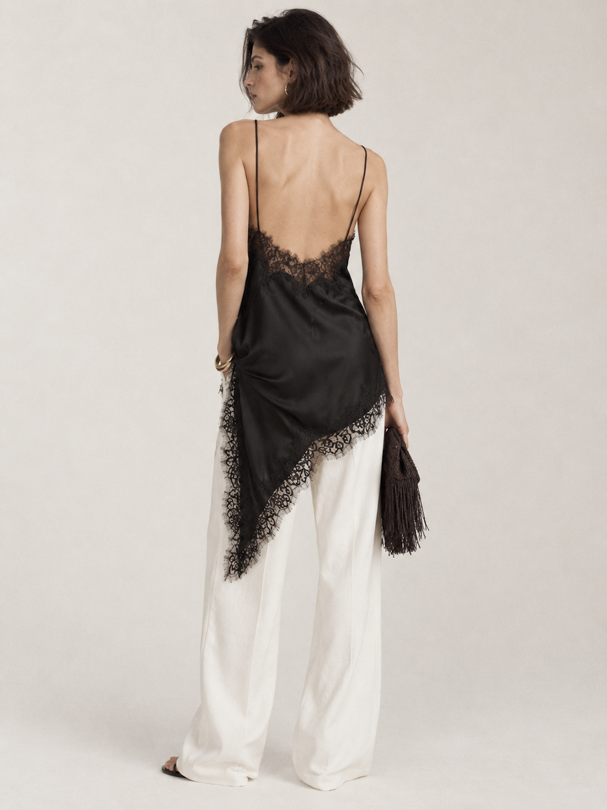 Back view of the Black Elévaison Renata Sleeveless Top, showing slim straps and the lace-trimmed asymmetric hem.