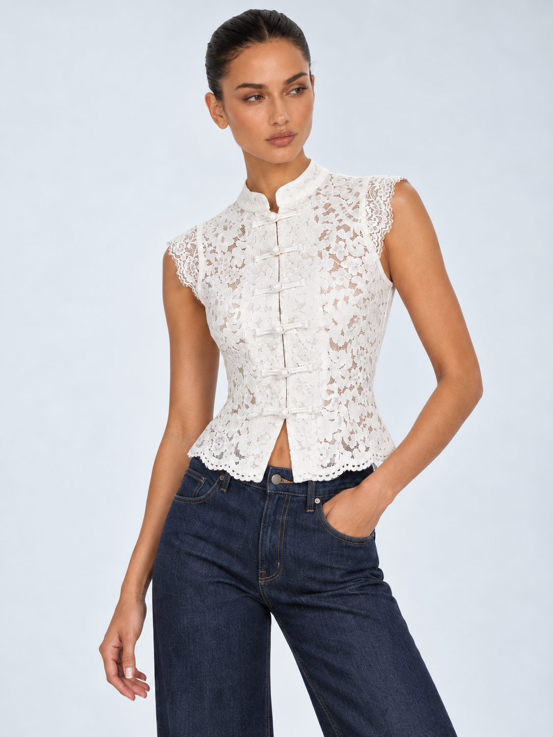 Elévaison Isadora Blouse in white, close-up front view showing the stand collar, frog buttons and scalloped lace trim against a pale blue studio background.