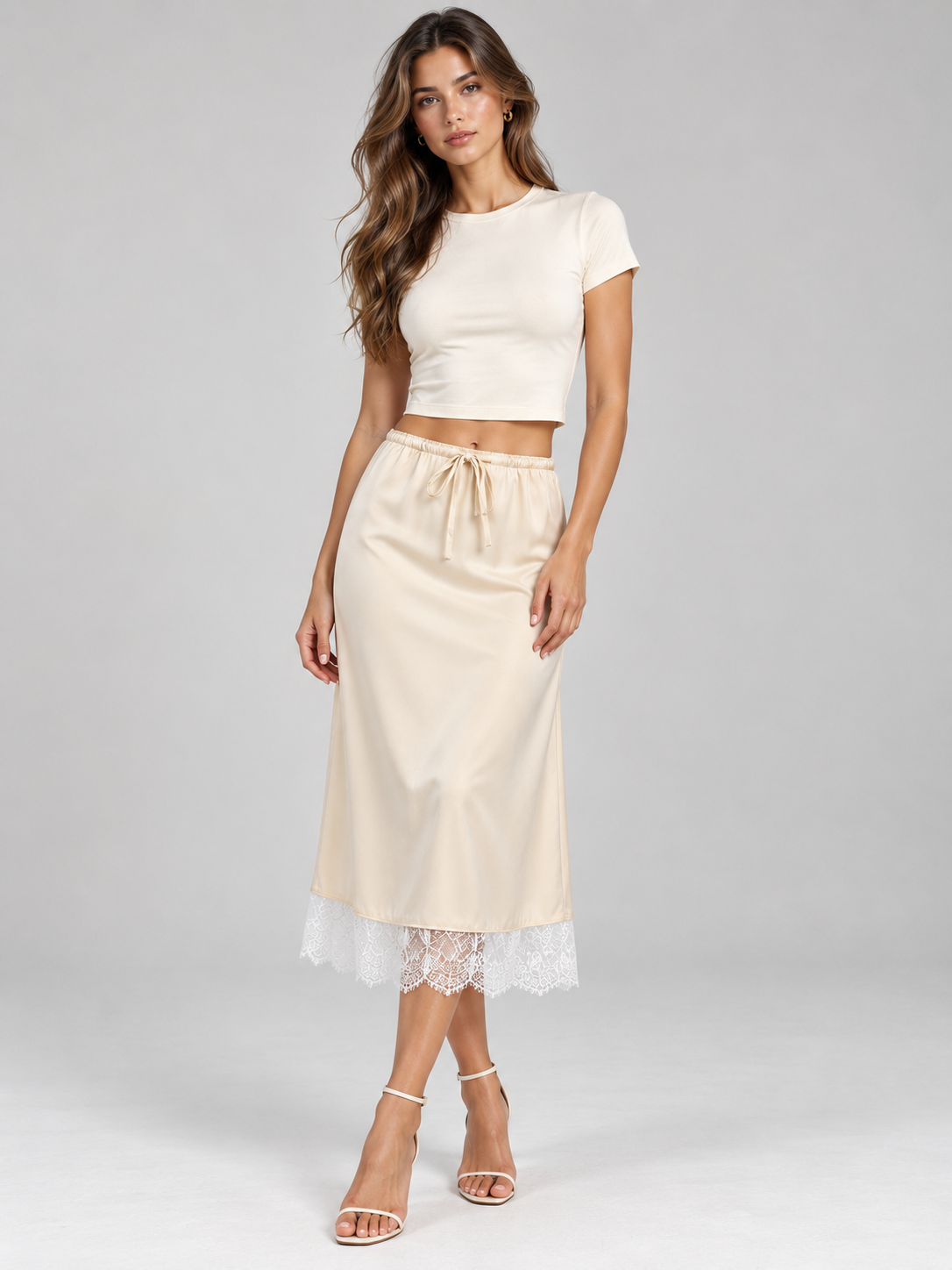 Elévaison Pearl Skirt in apricot, full-length front view showing a drawstring waist and white lace-trimmed midi hem, styled with a white cropped T-shirt against a light gray studio background.