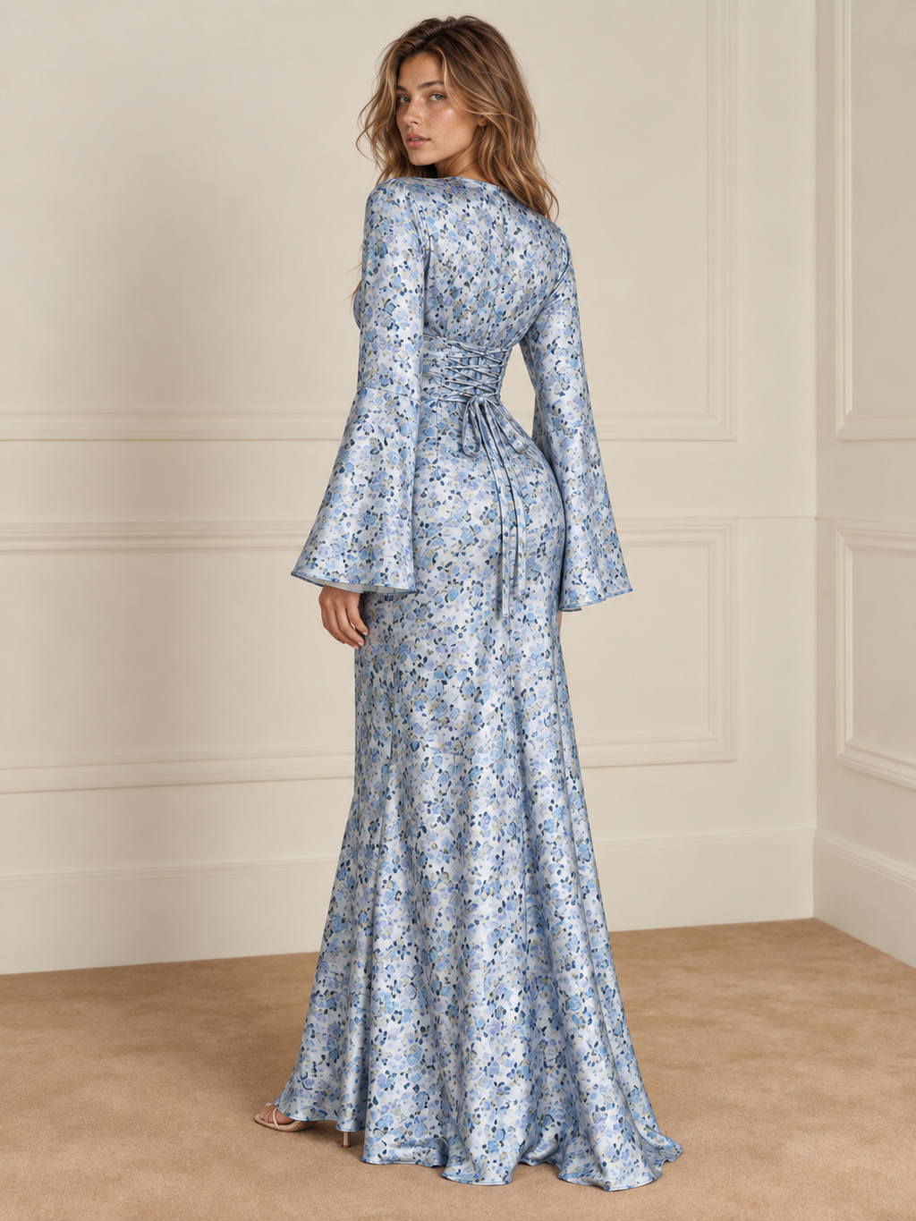 Elévaison Diana Dress in blue with a fine floral print, back view showing the fitted waist and flared sleeves against a warm cream paneled studio background.