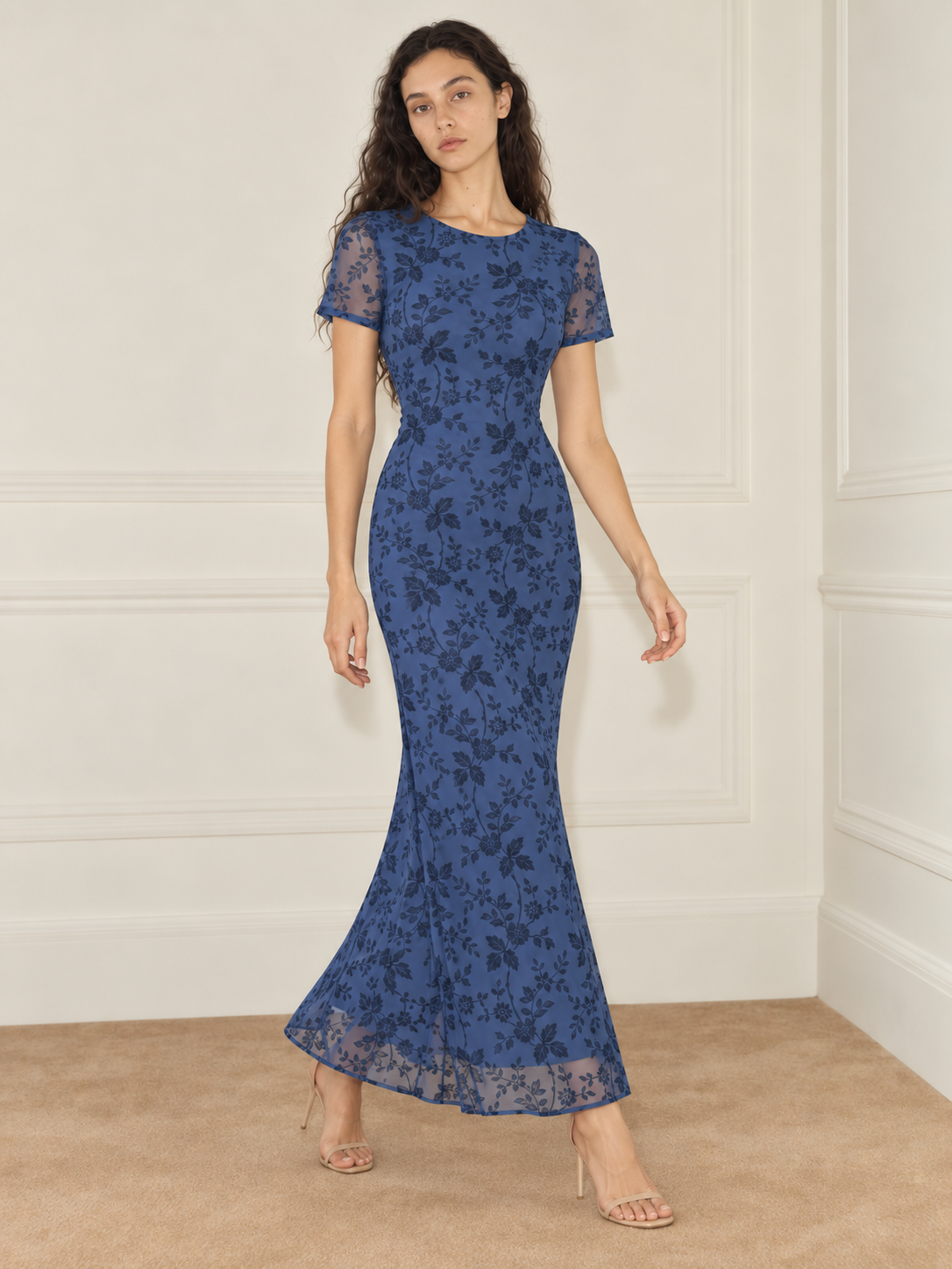 Elévaison Juliette Dress in blue, full-length front view showing a fitted silhouette, short sheer sleeves and a dark floral overlay against a warm cream paneled studio background.