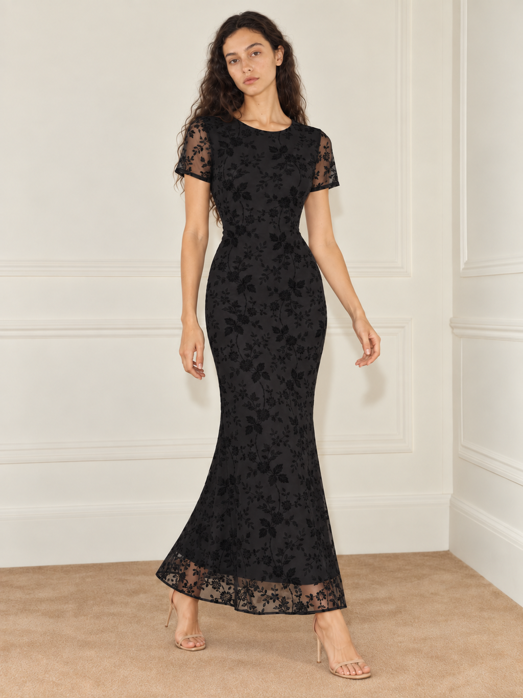 Elévaison Juliette Dress in black, front view showing a fitted silhouette, short sheer sleeves and sheer floral hem against a warm cream paneled studio background.