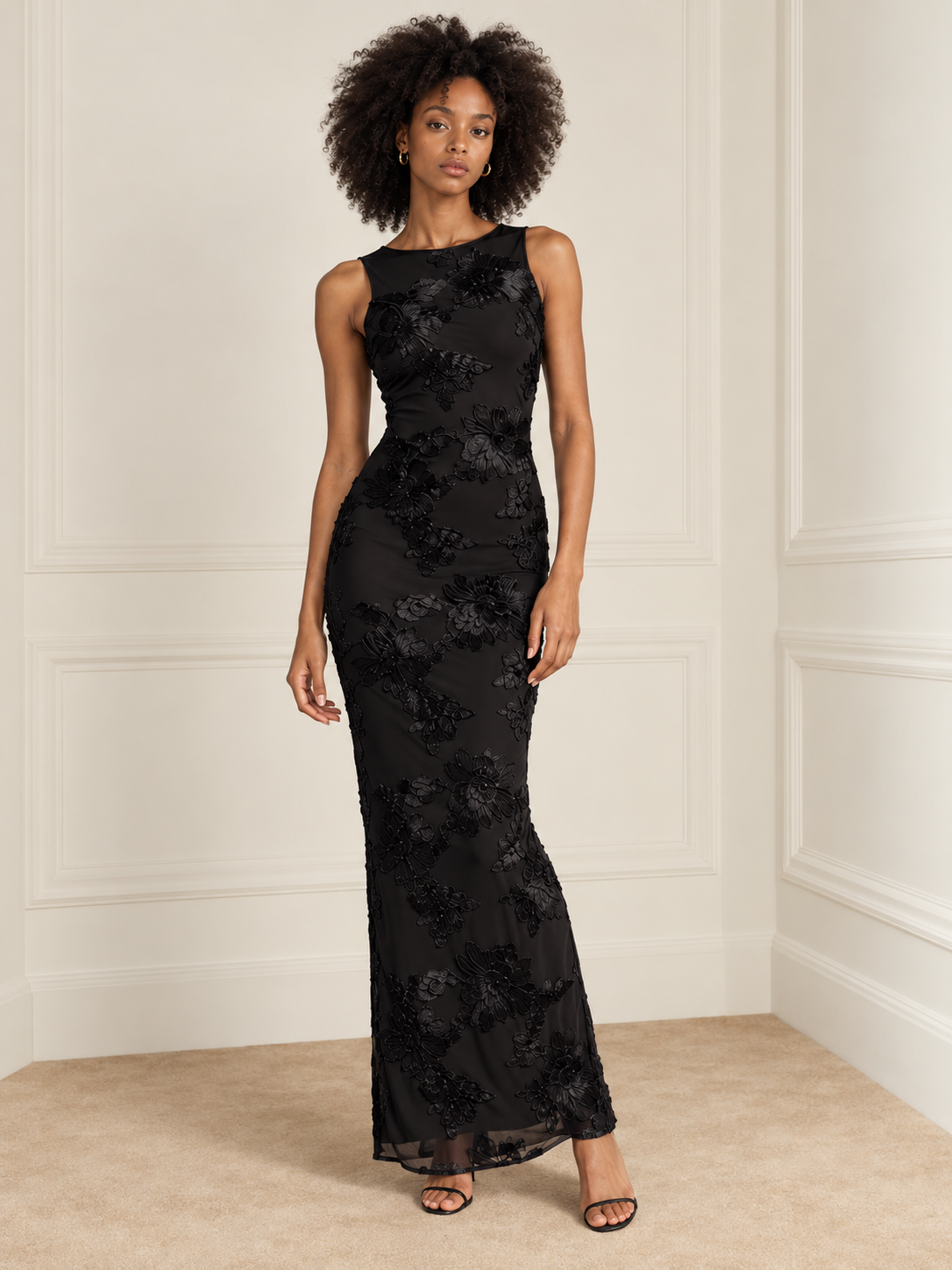 Elévaison Grace Dress in black, full-length front view showing a sleeveless fitted silhouette and dimensional floral embroidery against a warm cream paneled studio background.