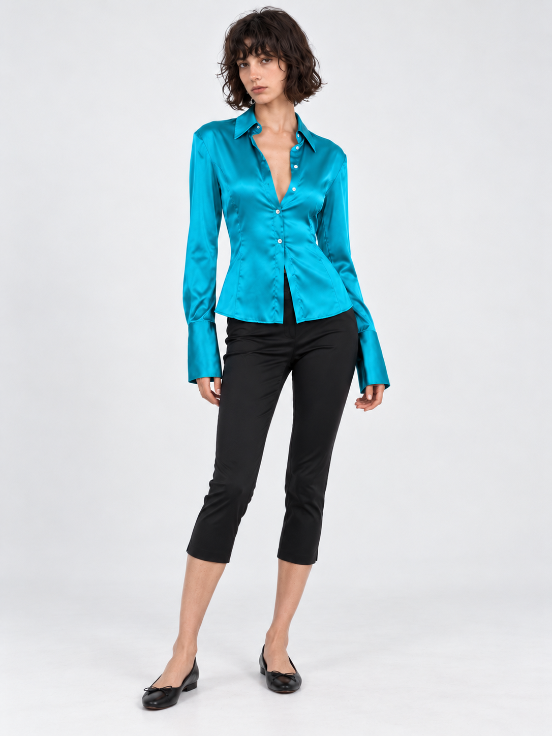 A model wears the Elévaison Adrienne Shirt in Turquoise Blue, showing its fitted waist and long cuffs against a light gray backdrop.