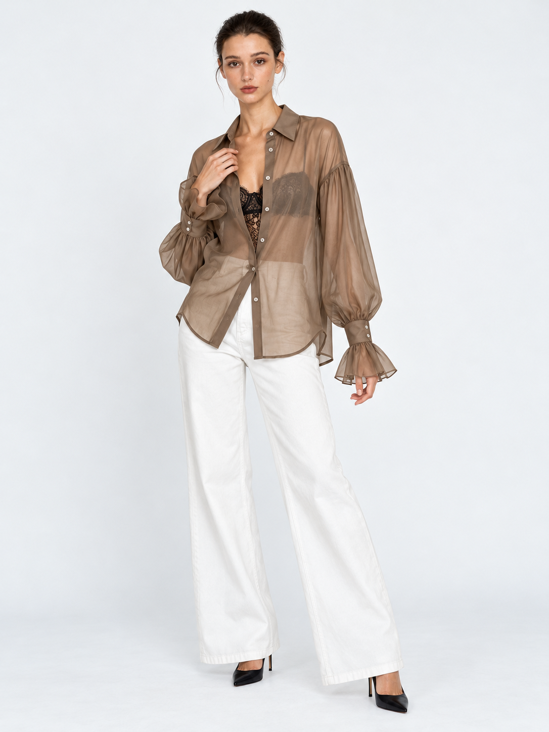 A model touches the collar of the Elévaison Florence Blouse in Khaki, showing its relaxed shape against a light gray studio backdrop.