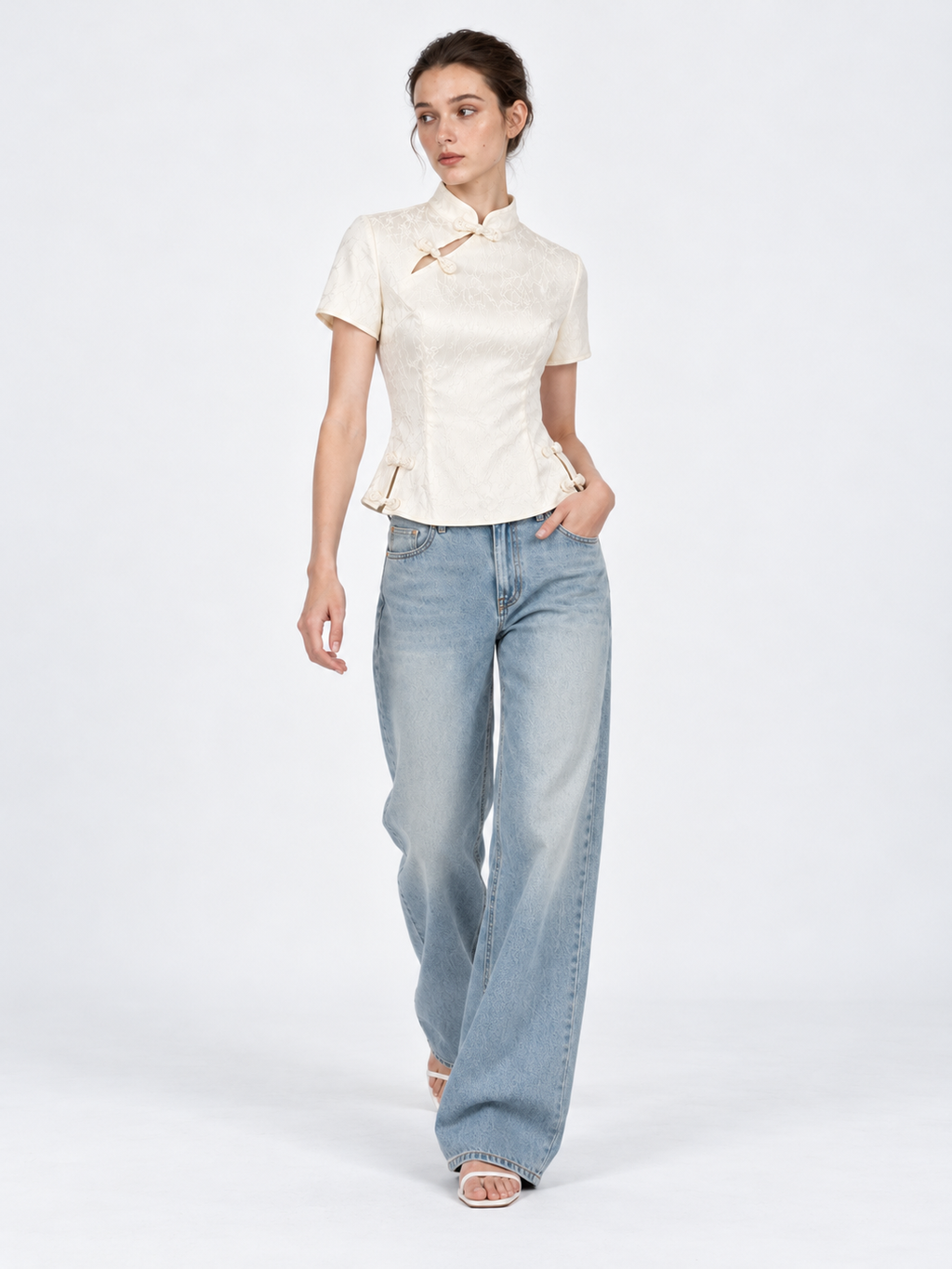 A model steps forward in the Elévaison Beatrice Blouse in White, with short sleeves and frog closures against a light gray backdrop.