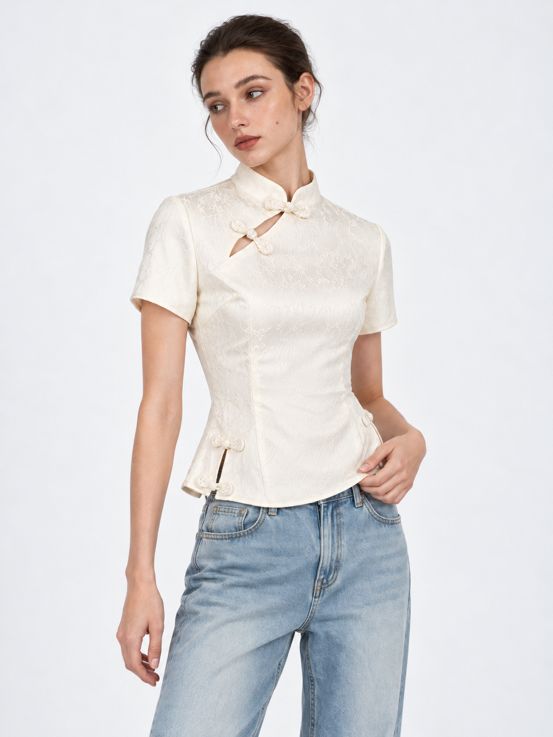 A closer view of the Elévaison Beatrice Blouse in White shows its mandarin collar and frog closures against a light gray backdrop.