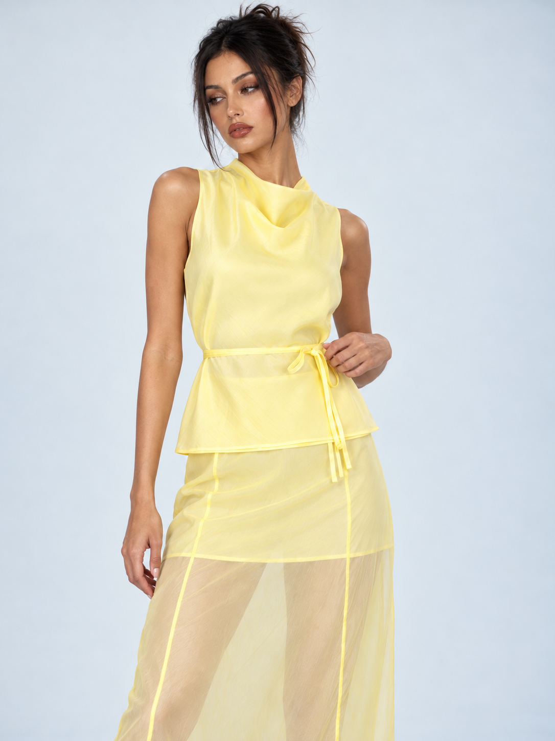 A closer view of the Elévaison Alessia Two Piece in Yellow shows its draped neckline and waist tie against a light gray backdrop.
