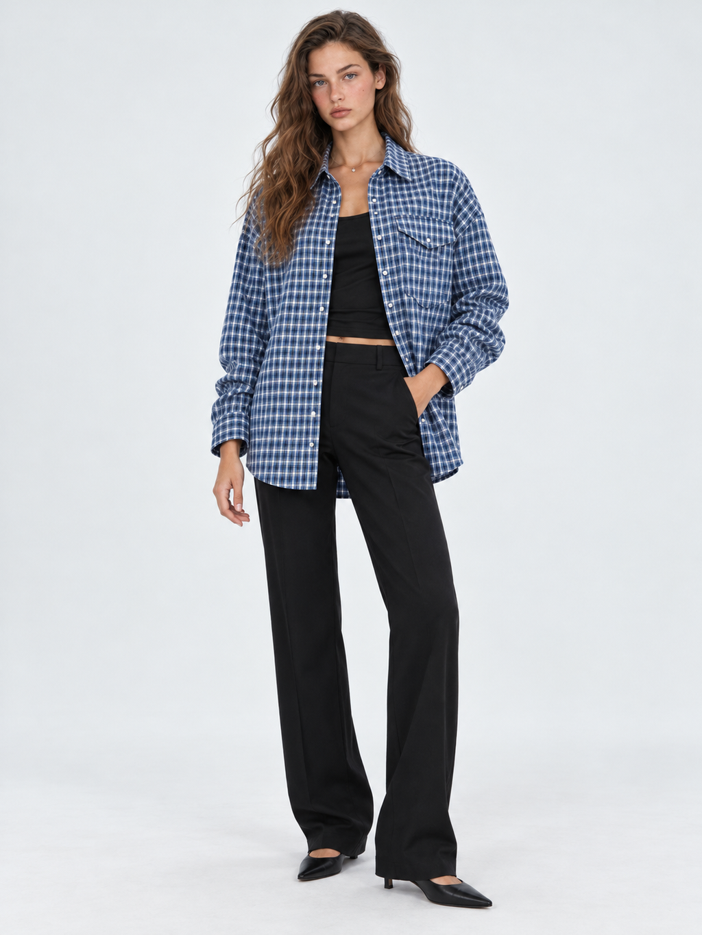 A model wears the Elévaison Audrey Cotton Shirt in Twilight Check open over a black top against a light gray studio backdrop.