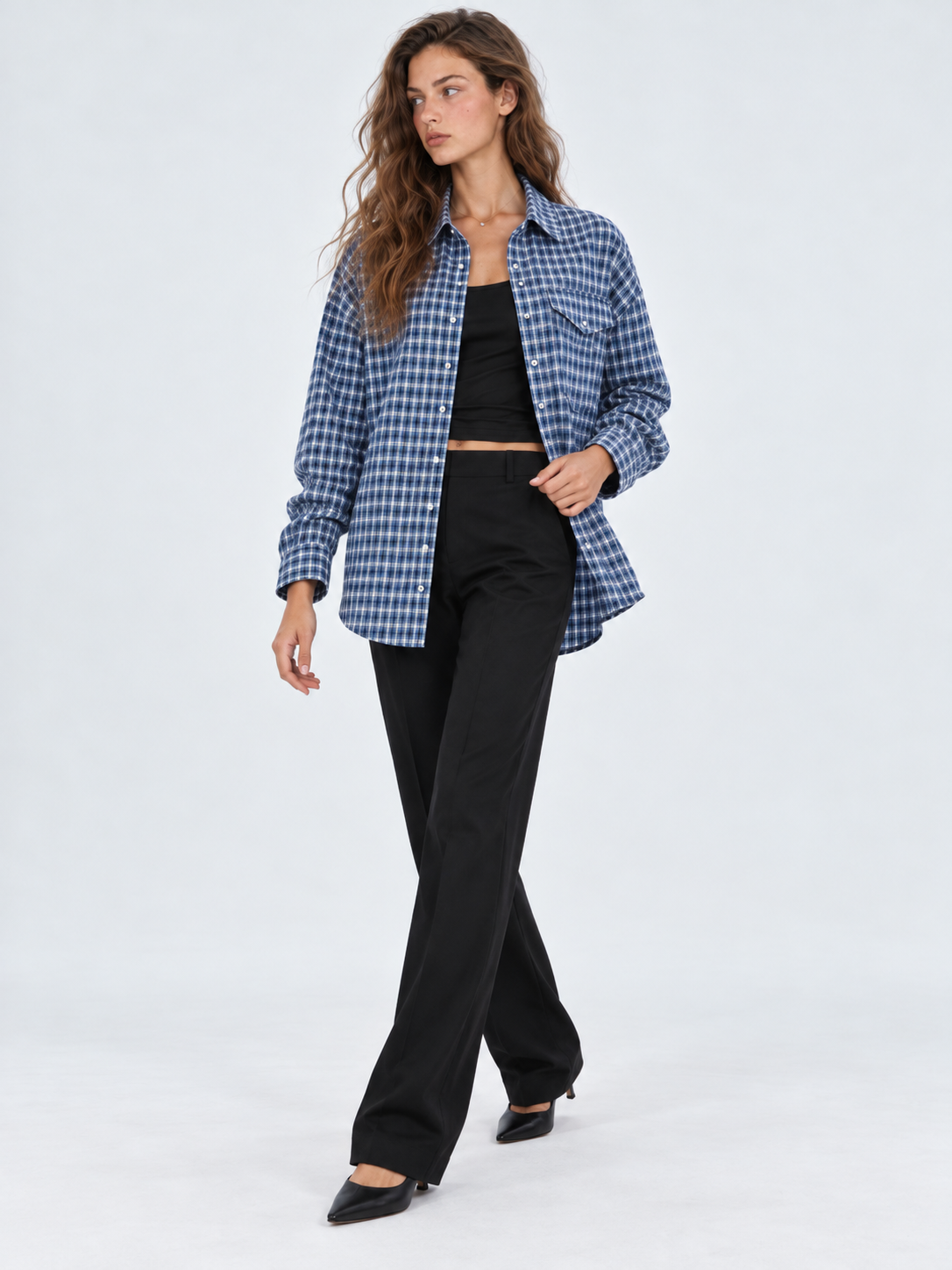 A model steps forward in the Elévaison Audrey Cotton Shirt in Twilight Check, its open hem moving against a light gray backdrop.