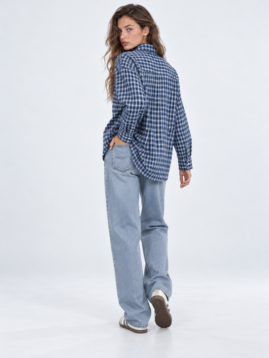 A model looks back in the Elévaison Audrey Cotton Shirt in Twilight Check, showing its relaxed back against a light gray backdrop.