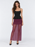 A model faces forward in the Elévaison Simone Skirt in Burgundy, showing its sheer layer and short lining against a gray backdrop.