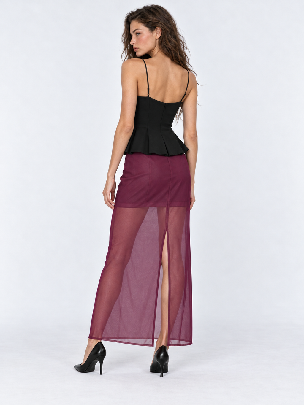 A rear view of the Elévaison Simone Skirt in Burgundy shows its long back slit and short lining against a light gray backdrop.
