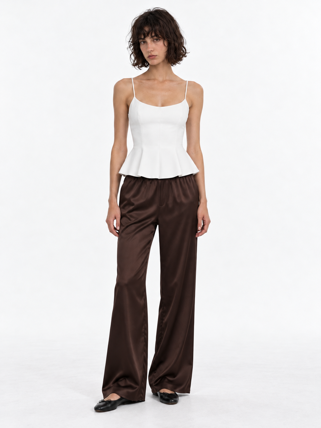 A model wears the Elévaison Helena Pants in Brown, with a gathered waistband and flowing wide legs against a light gray backdrop.