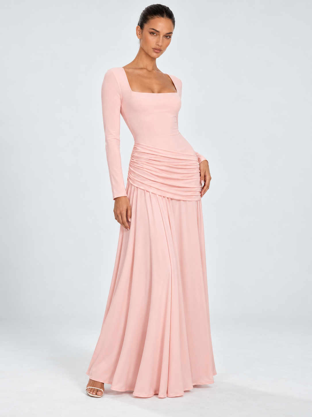 A model wears the Elévaison Arabella Dress in Pink, with long sleeves and a gathered hip panel against a light gray backdrop.