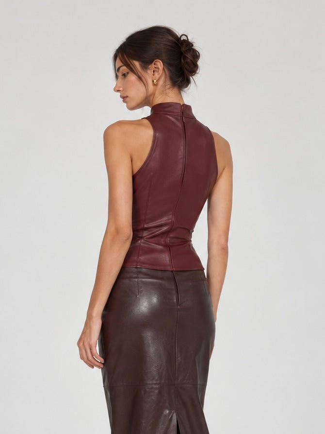 A model turns away in the Elévaison Carmen Top in Burgundy, showing its back zipper and fitted seams against a light gray backdrop.